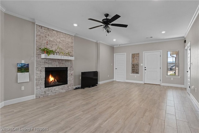 unfurnished living room with ornamental molding, a ceiling fan, light wood-style floors, a stone fireplace, and baseboards