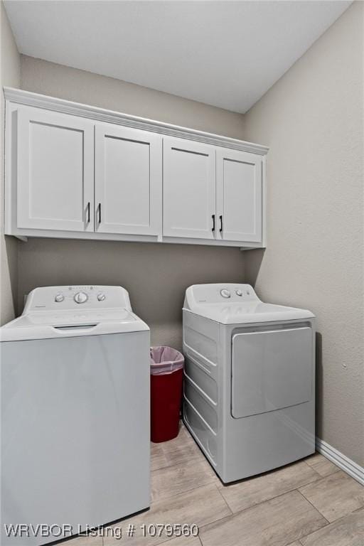 clothes washing area featuring baseboards, cabinet space, light wood-style floors, and washing machine and dryer