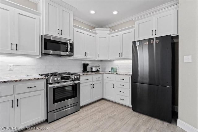 kitchen featuring tasteful backsplash, appliances with stainless steel finishes, white cabinets, crown molding, and light stone countertops