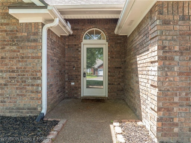 doorway to property featuring brick siding