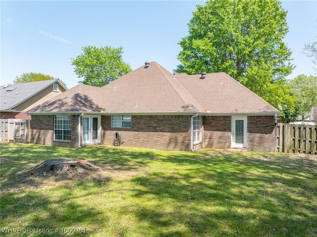back of property with fence, brick siding, and a yard