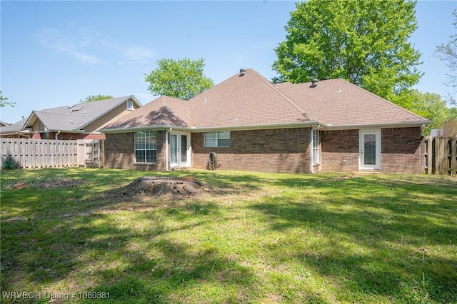 back of house featuring brick siding, a lawn, and a fenced backyard