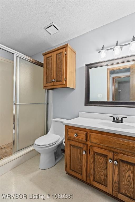 bathroom featuring toilet, vanity, visible vents, and a stall shower