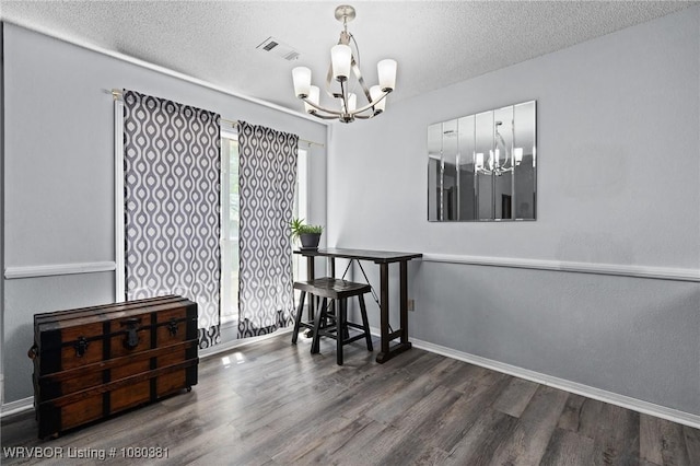 dining space featuring baseboards, wood finished floors, an inviting chandelier, and a textured ceiling