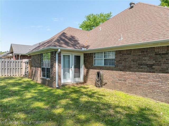 back of property featuring fence, a shingled roof, a yard, french doors, and brick siding
