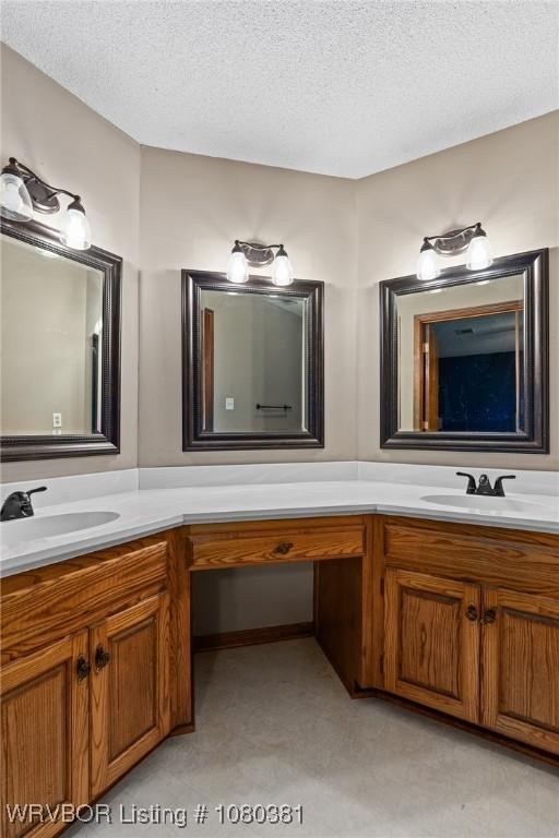 full bath featuring a sink, a textured ceiling, and double vanity