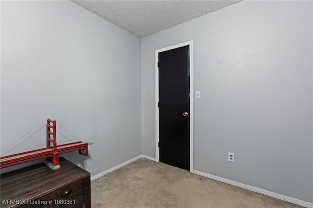 unfurnished room with light carpet, a textured ceiling, and baseboards
