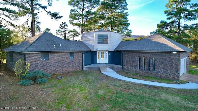 rear view of property with a garage and a lawn