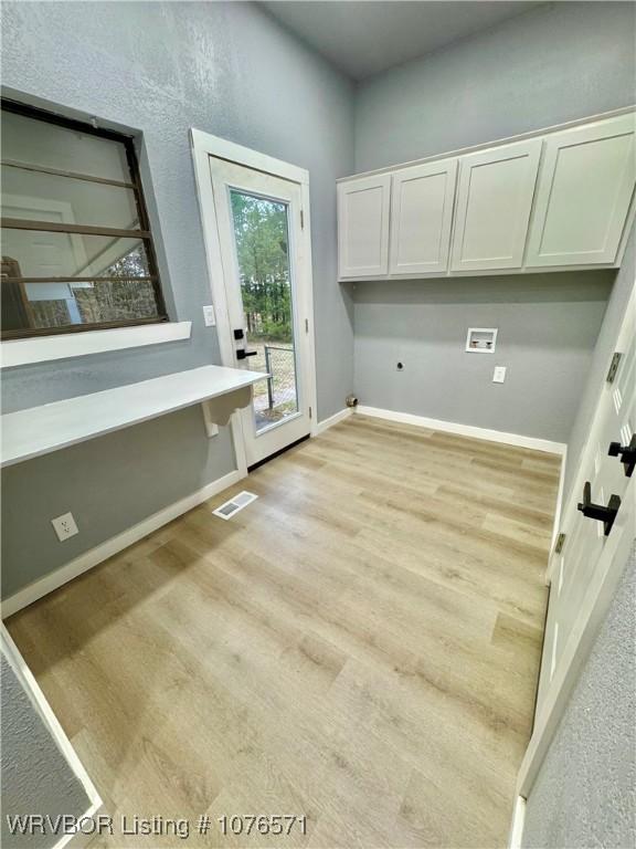 laundry area featuring cabinets, washer hookup, and light hardwood / wood-style floors