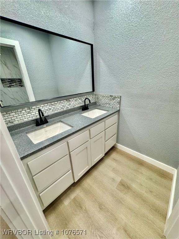 bathroom featuring vanity, wood-type flooring, and tasteful backsplash