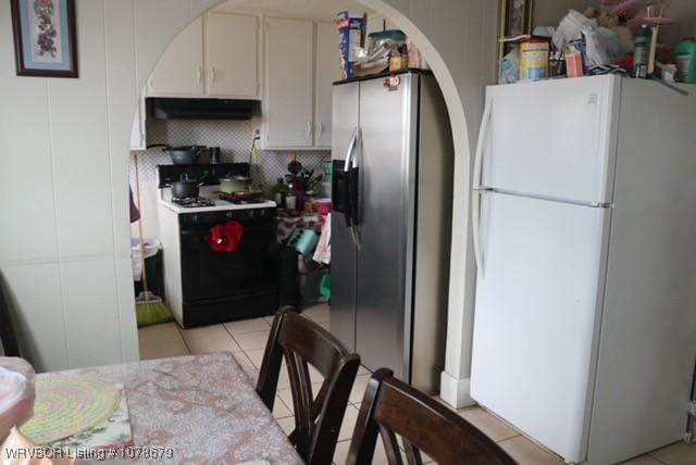 kitchen featuring tasteful backsplash, white cabinets, range with gas cooktop, freestanding refrigerator, and stainless steel refrigerator with ice dispenser