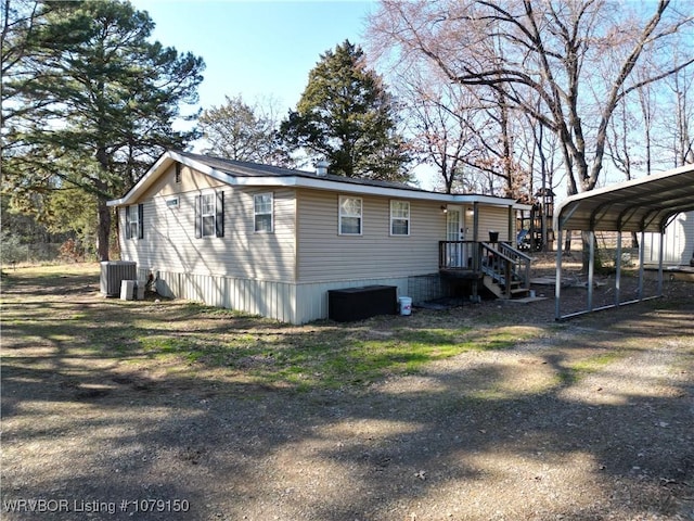 view of side of property featuring central air condition unit, dirt driveway, and a carport