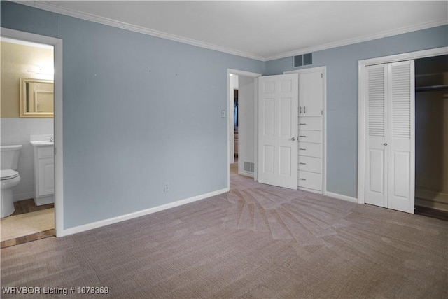 unfurnished bedroom with crown molding, ensuite bath, and carpet