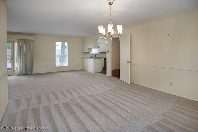 unfurnished living room featuring ornamental molding, light colored carpet, and an inviting chandelier