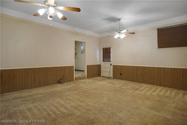 carpeted empty room with wood walls and ceiling fan