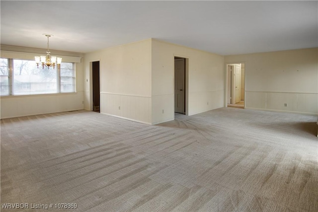 carpeted spare room with a notable chandelier