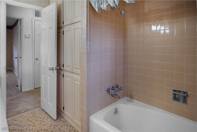 bathroom featuring tile patterned flooring and tiled shower / bath