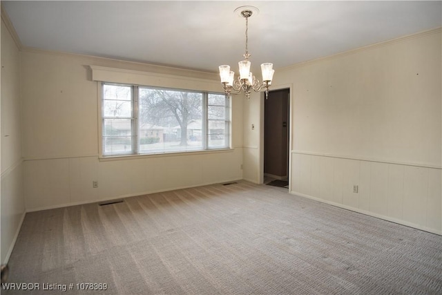 carpeted spare room with crown molding and a chandelier