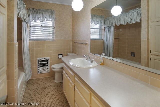 full bathroom with heating unit, vanity, tile walls, ornamental molding, and shower / tub combo with curtain