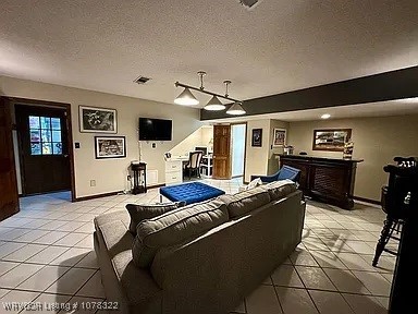 tiled living room featuring a textured ceiling