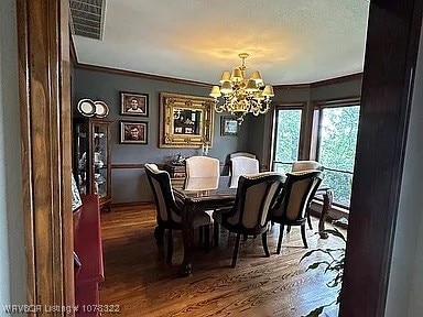 dining space featuring dark hardwood / wood-style flooring, crown molding, and a chandelier