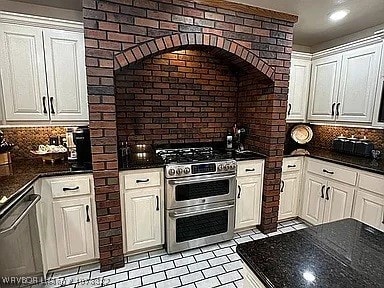 kitchen with decorative backsplash, brick wall, white cabinetry, and appliances with stainless steel finishes