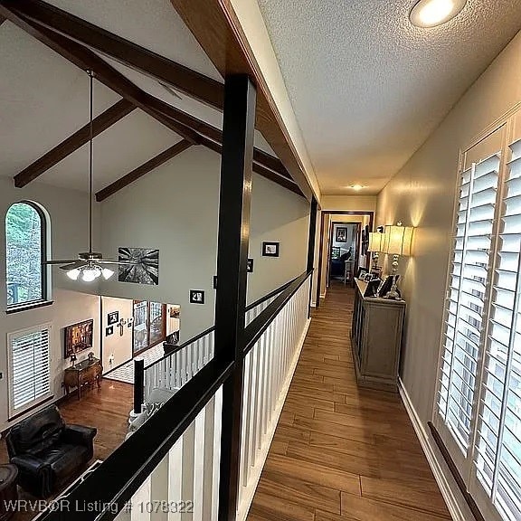 hall featuring beam ceiling, dark hardwood / wood-style flooring, a textured ceiling, and high vaulted ceiling