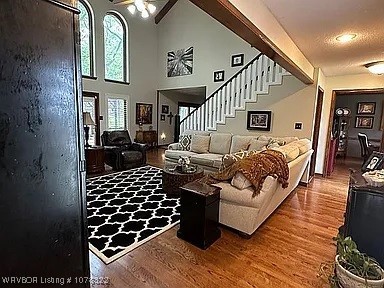 living room with a textured ceiling, ceiling fan, wood-type flooring, and a high ceiling