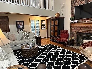 living room featuring a fireplace, a towering ceiling, and wood-type flooring