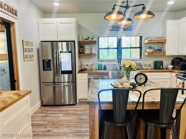 kitchen with white cabinets, stainless steel fridge, a center island, and a breakfast bar