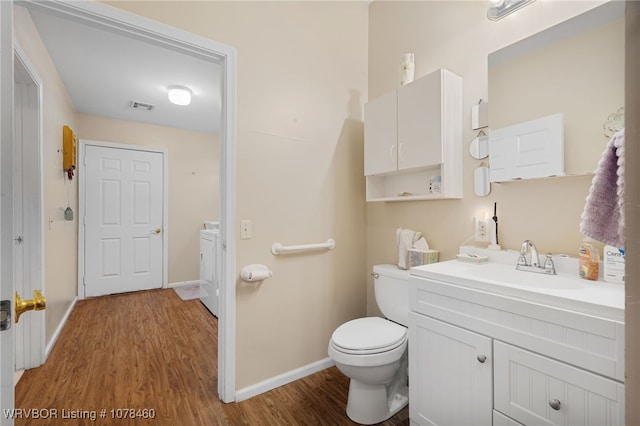 bathroom featuring toilet, washer and clothes dryer, wood-type flooring, and vanity