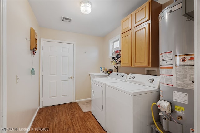 washroom with cabinets, washer and clothes dryer, light hardwood / wood-style flooring, and gas water heater