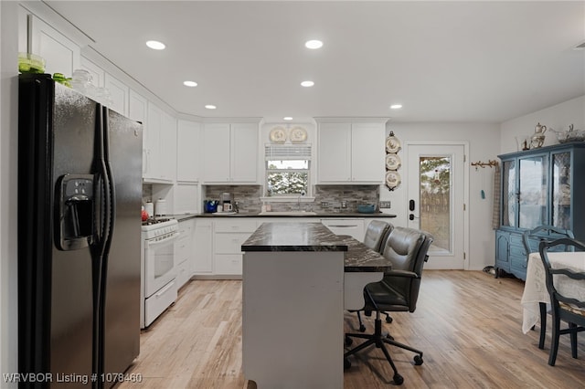 kitchen featuring black refrigerator with ice dispenser, a kitchen island, white cabinetry, and white range with gas cooktop