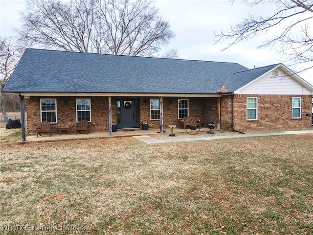 ranch-style home with a patio area, brick siding, a shingled roof, and a front yard