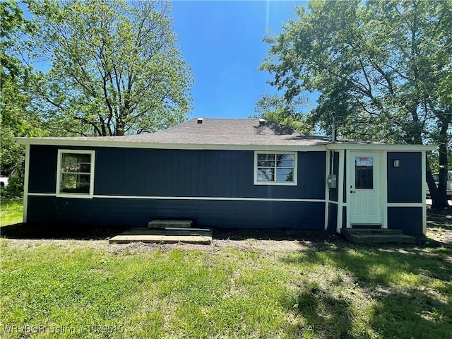 back of property featuring a yard, a shingled roof, and entry steps