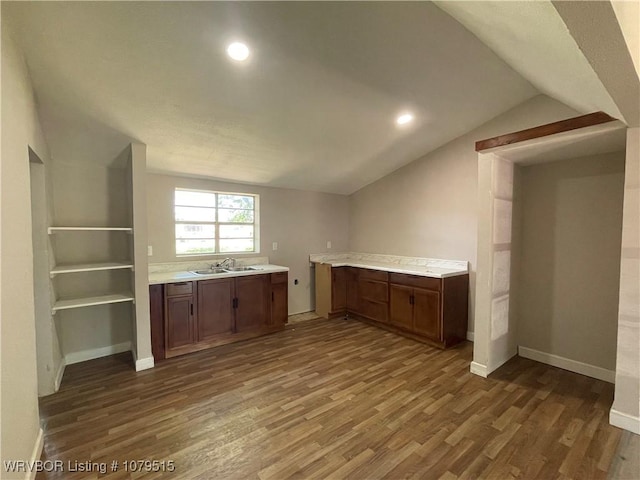 kitchen with light countertops, dark wood-style flooring, a sink, and lofted ceiling