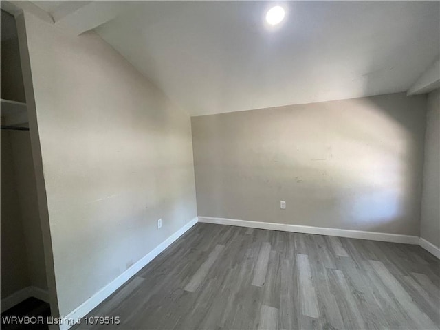 empty room with baseboards, wood finished floors, and lofted ceiling