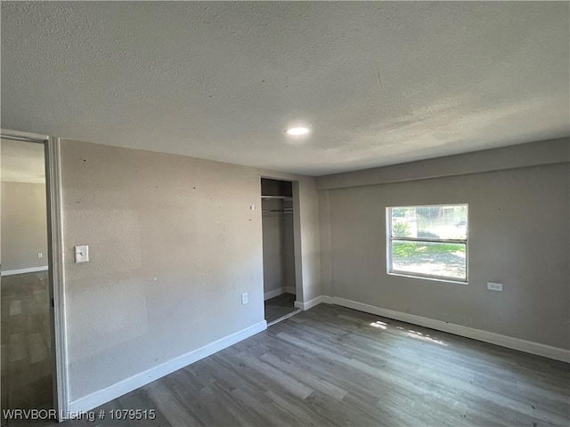 unfurnished bedroom with a closet, wood finished floors, baseboards, recessed lighting, and a textured ceiling