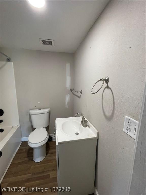 full bath featuring visible vents, wood finished floors, shower / washtub combination, vanity, and toilet