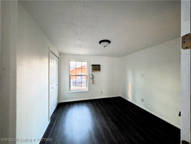 unfurnished room featuring a wall mounted air conditioner and dark hardwood / wood-style flooring