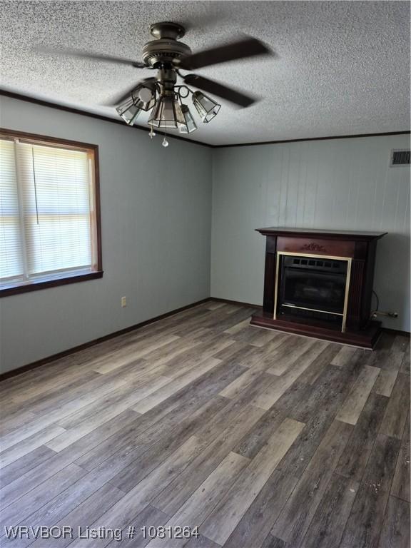 1382 6th St, Waldron, AR 72958 - unfurnished living room featuring a ceiling fan, a fireplace with raised hearth, wood finished floors, and a textured ceiling