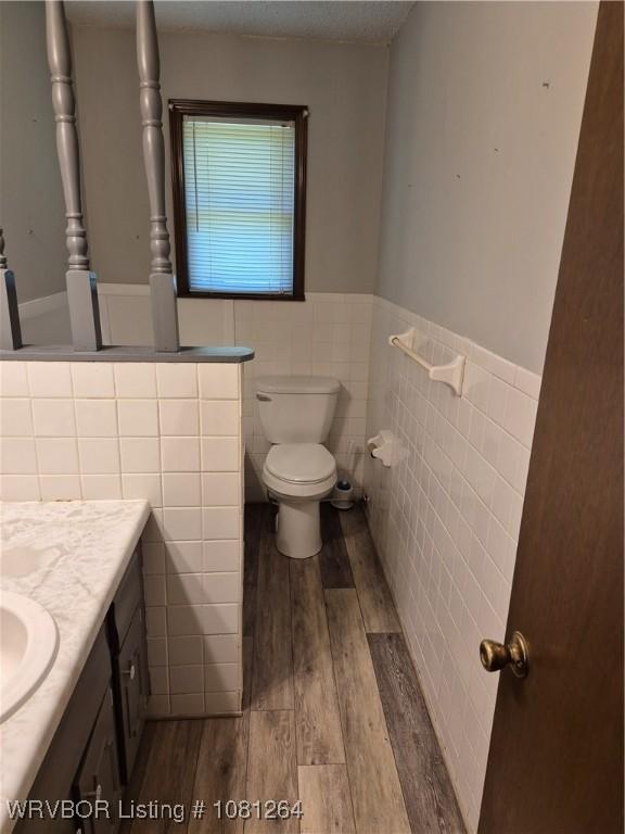 1382 6th St, Waldron, AR 72958 - bathroom featuring wood finished floors, vanity, wainscoting, toilet, and tile walls