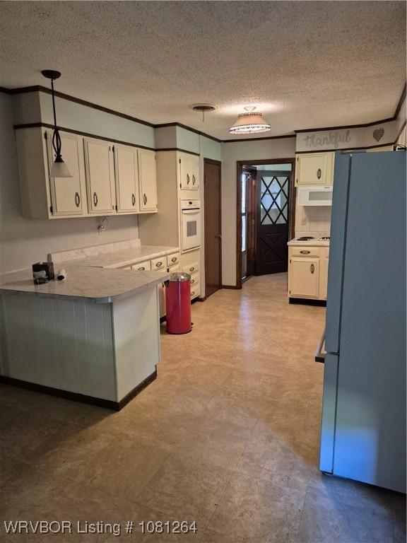 1382 6th St, Waldron, AR 72958 - kitchen with freestanding refrigerator, oven, a textured ceiling, light countertops, and white cabinets
