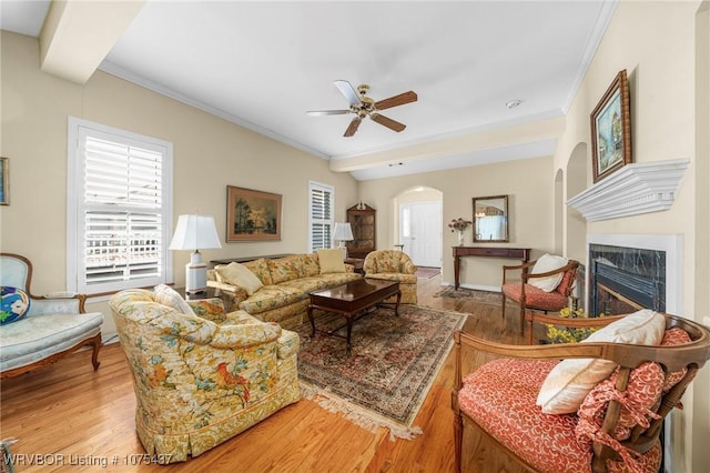 living room with a premium fireplace, ceiling fan, wood-type flooring, and ornamental molding