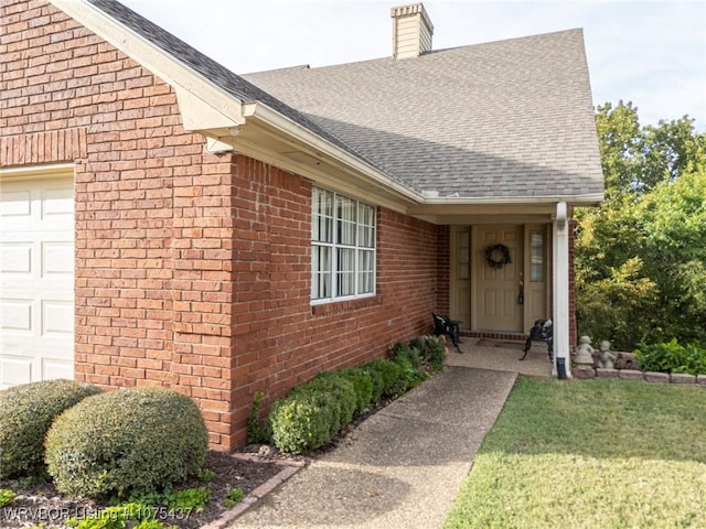 entrance to property featuring a garage and a lawn