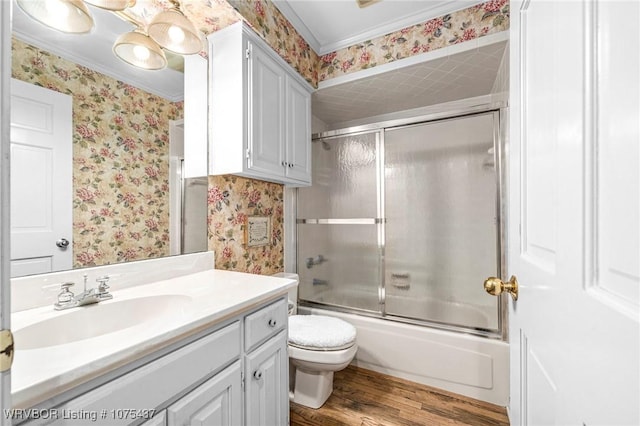 full bathroom with vanity, crown molding, hardwood / wood-style flooring, enclosed tub / shower combo, and toilet