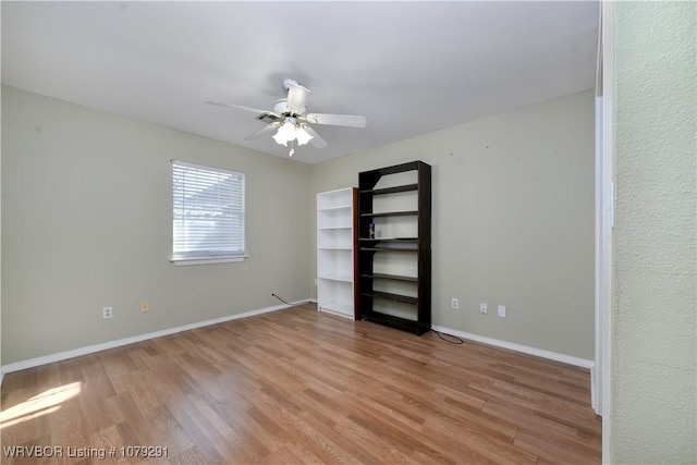 empty room with a ceiling fan, light wood-style flooring, and baseboards