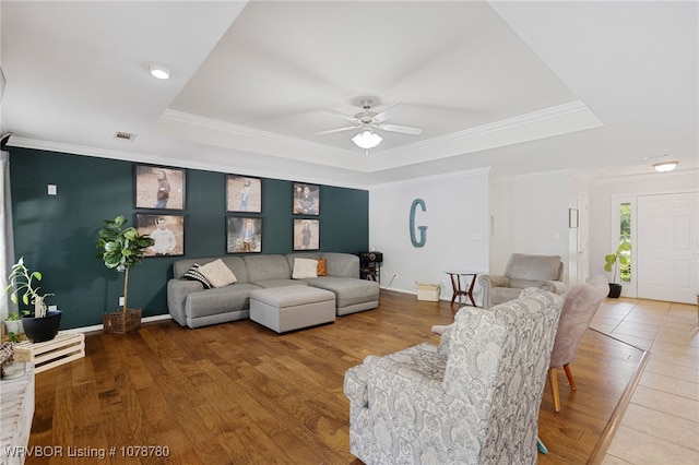 living room with a raised ceiling, crown molding, and hardwood / wood-style flooring