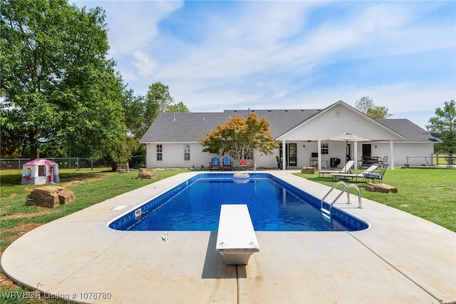 view of swimming pool featuring a yard, a diving board, and a patio area