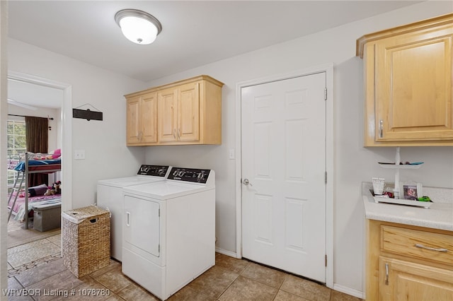 clothes washing area with cabinets, washer and dryer, and light tile patterned flooring